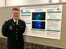 Dr. Casey Wilgenbusch beside presentation poster