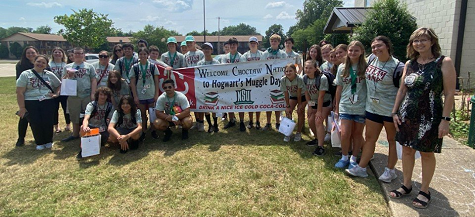 Choctaw Nation STEAM Camp attendees posing with the banner they signed, along with their sponsors, and Dr. Meagan Moreland, Endowed Chair of Recruitment and Retention in Education and Dr. Kelli Carney, Assistant Dean of the College of Education.  