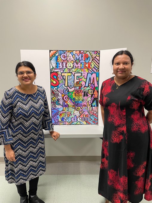 Drs. Janaki Iyer and Dulanjani Wijayasekara next to the collage created by Camp Biomed students