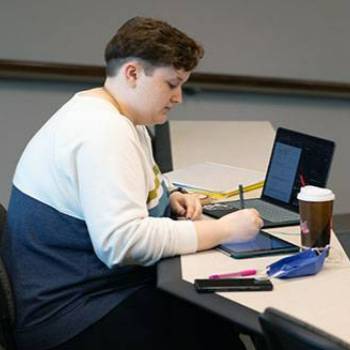 Student studying at table with computer and books