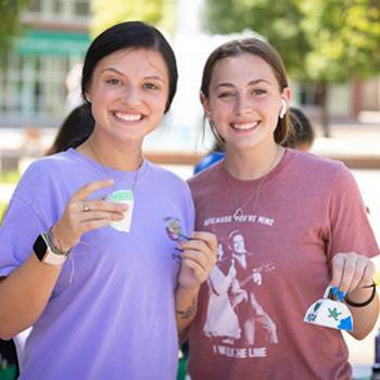 Two students holding painted cowbells